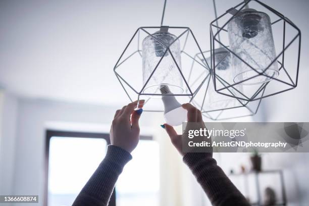 close up of female hands installing eco light bulb. - ceiling lamp stock pictures, royalty-free photos & images