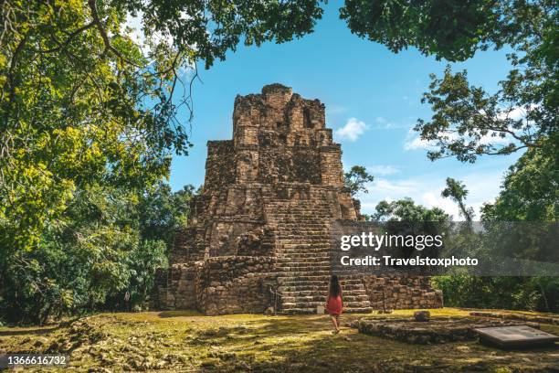 young woman standing in front of ruins of a mayan pyramid in the mexican jungle - quintana roo stock-fotos und bilder