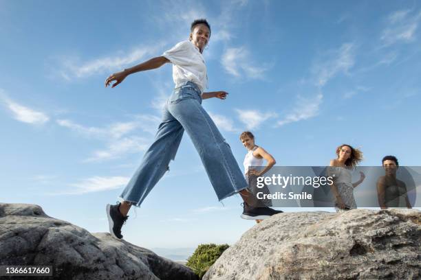 a beautiful young woman stepping onto a boulder. - african travel smile foto e immagini stock