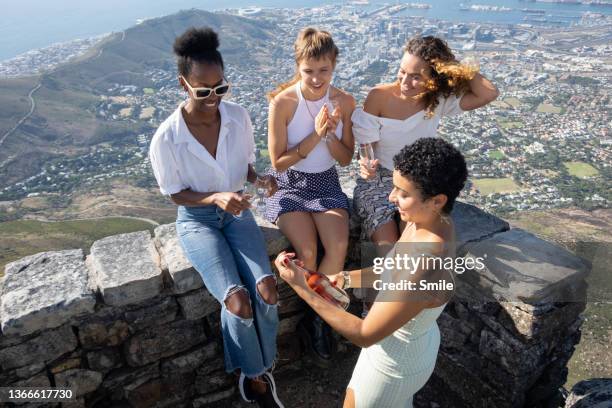 a group of girlfriends looking at bottle with anticipation. - group of beautiful people stock pictures, royalty-free photos & images