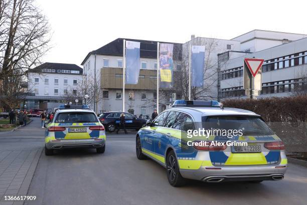 Police cars stand outside a building of Heidelberg University following a shooting that left the attacker dead, one victim dead and three others...