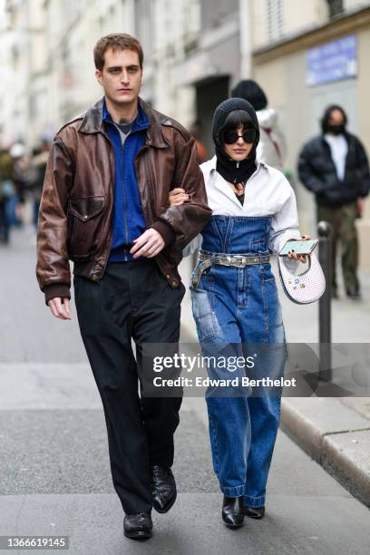 Guest wears a black t-shirt, a pale gray V-neck wool pullover, a blue high neck zipper sweater, a brown shiny leather oversized jacket, black suit...