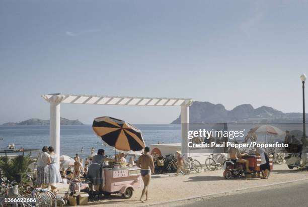 Ice cream sellers and visitors on the beach and promenade in the town of La Ciotat in the Bouches-du-Rhone department of southern France circa 1960.