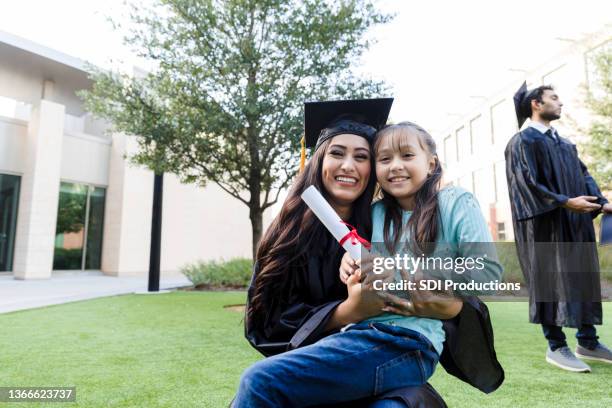 joven adulto graduado posa con sobrina y diploma - sobrina fotografías e imágenes de stock