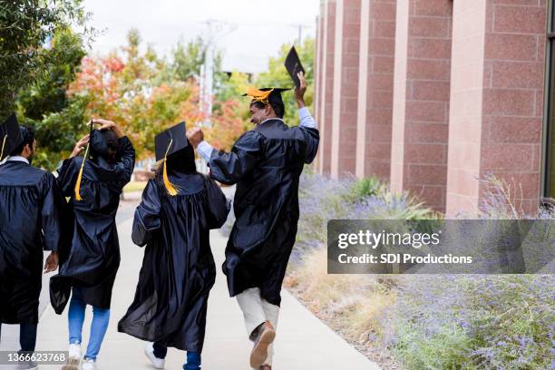 diverse graduates walk out to family after ceremony - graduates stockfoto's en -beelden