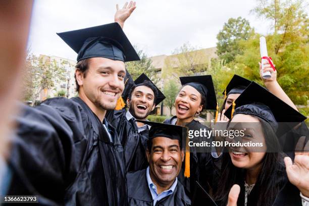 grupo de amigos diversos toma una foto alegre después de la graduación - university students celebrate their graduation fotografías e imágenes de stock