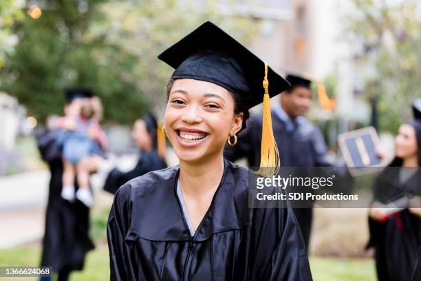 after graduation ceremony, woman smiles for photo - graduation clothing stockfoto's en -beelden