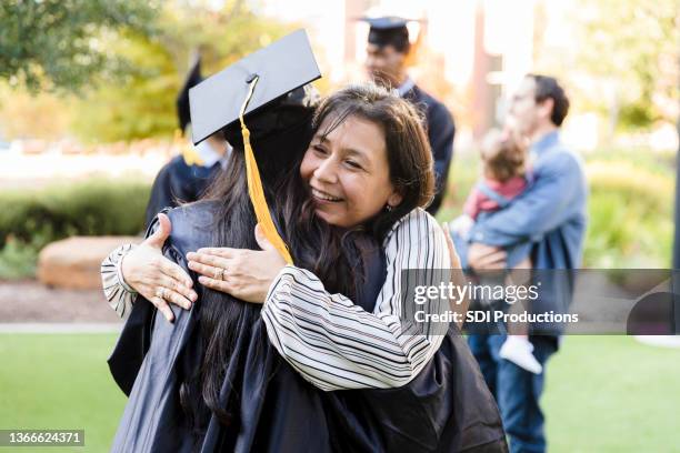 proud mother hugs unrecognizable daughter after graduation ceremony - kids proud stock pictures, royalty-free photos & images