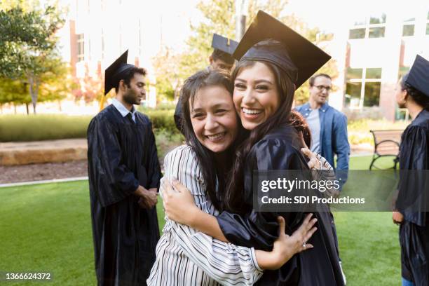 smiling college graduate stands cheek to cheek with mom - father daughter college stock pictures, royalty-free photos & images