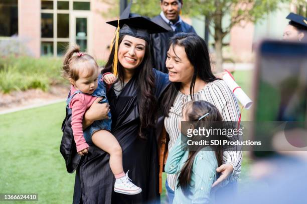 unrecognizable person takes photo of multi-generation family at graduation - mature student stockfoto's en -beelden
