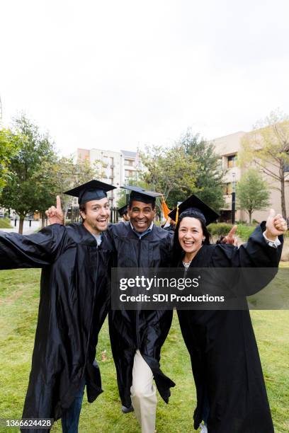 three friends cheer and smile after graduation ceremony - diverse graduation stock pictures, royalty-free photos & images
