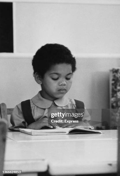 Schoolgirl reads a book in the classroom, UK, 21st September 1960.