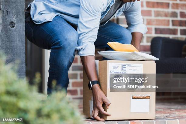 unrecognizable homeowner bends down to retrieve packages on door stoop - stoop stock pictures, royalty-free photos & images