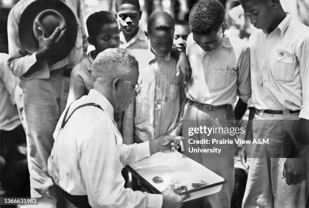 Dr. E.B. Evans, State Leader, Negro Extension Work, Prairie View, Texas, and negro 4-H Club boys looking at exhibits of snake at Wildlife...