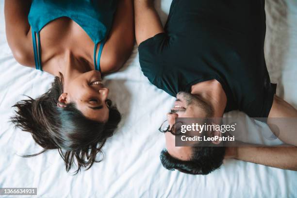young couple in love, laying down on the bed - tired couple stock pictures, royalty-free photos & images
