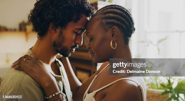 photo d’un jeune couple debout ensemble et partageant un moment intime à la maison - couple photos et images de collection