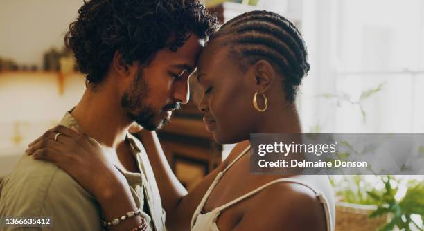 shot of a young couple standing together and sharing an intimate moment at home - human relationship stockfoto's en -beelden