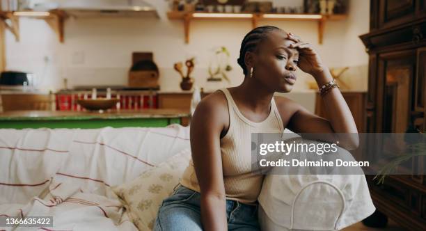 自宅のソファに一人で座ってストレスを感じている魅力的な若い女性のショット - せっかち ストックフォトと画像