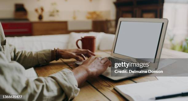 tiro cortado de um homem irreconhecível sentado sozinho em casa e usando seu laptop para calcular suas finanças - página da web - fotografias e filmes do acervo