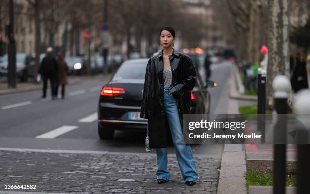 Fashion Week Guest wearing a black leather coat, a silver top and blue jeans outside Paco Rabanne on January 23, 2022 in Paris, France.