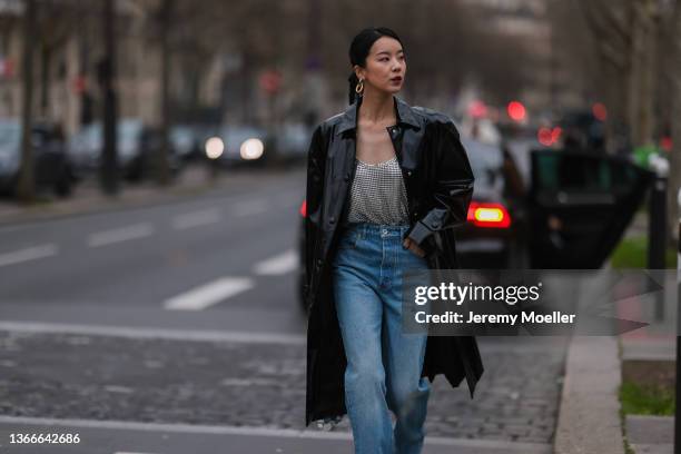 Fashion Week Guest wearing a black leather coat, a silver top and blue jeans outside Paco Rabanne on January 23, 2022 in Paris, France.