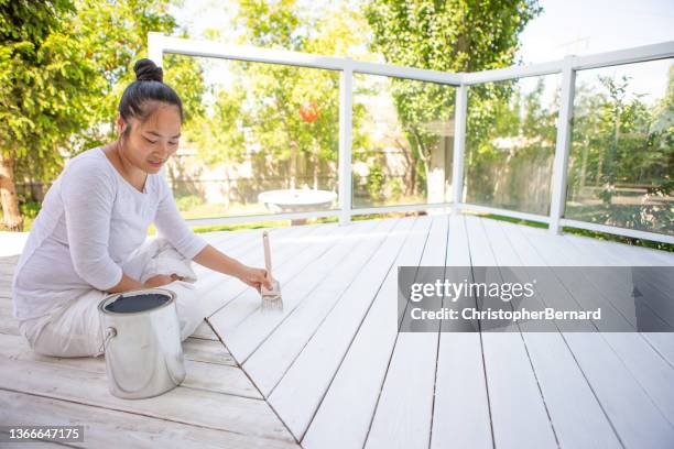 smiling asian woman painting deck - backyard deck stockfoto's en -beelden