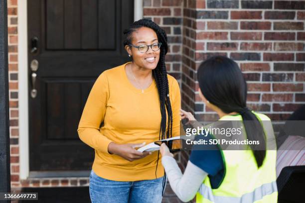 woman listens to instructions to sign for package - answering door stock pictures, royalty-free photos & images