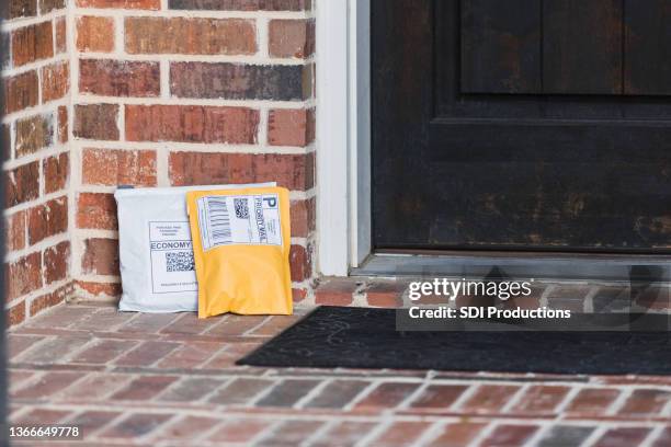 two packages dropped off on front stoop left unprotected - brick house door stock pictures, royalty-free photos & images