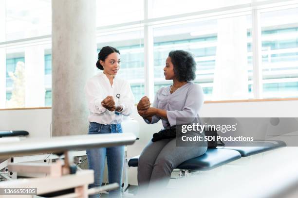 woman with injured wrist does exercise during physical therapy - african injured stock pictures, royalty-free photos & images