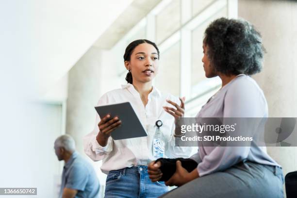 physical therapist gestures while asking woman questions about injury - hälsovård och medicin bildbanksfoton och bilder