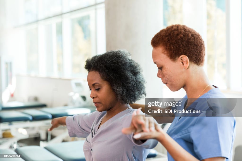 Woman learns arm and shoulder stretches from physical therapist
