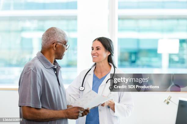 female doctor and senior patient discuss home healthcare options - doctor and patient talking imagens e fotografias de stock