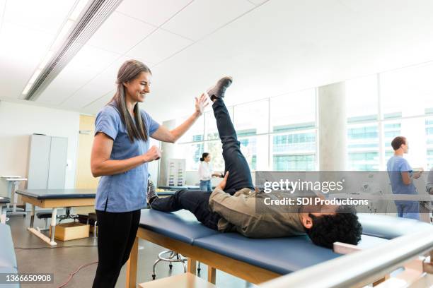männlicher patient versucht beinheben in der physiotherapie - examination table stock-fotos und bilder