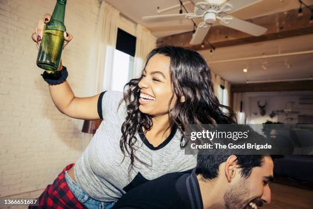 laughing friends having fun while drinking beer at house party - betrunken stock-fotos und bilder