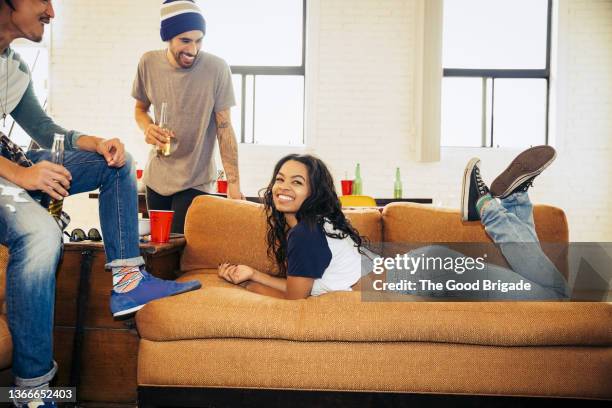 young woman lying on sofa with friends at party - lying on front stock pictures, royalty-free photos & images