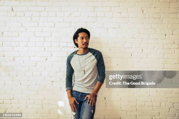 portrait of handsome man standing against brick wall - ��長袖 ストックフォトと画像