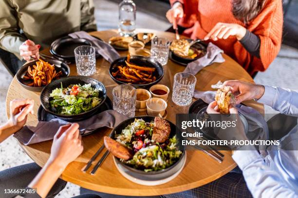 friends eating dinner in a modern restaurant - ronde tafel stockfoto's en -beelden