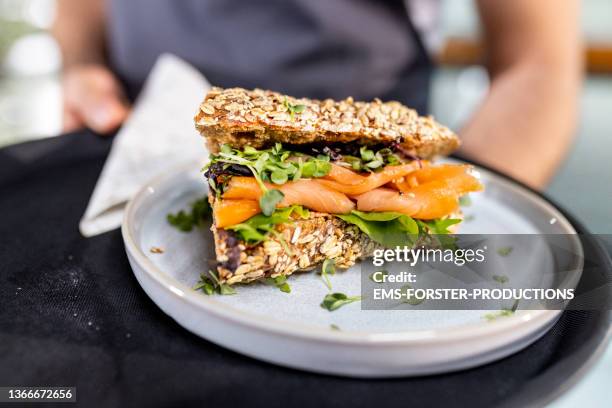 close up from fresh salmon sandwich serving from waiter - man tray food holding stockfoto's en -beelden