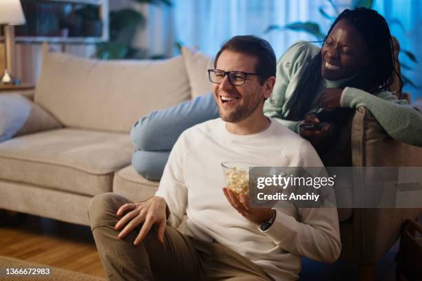 diverse couple watching movie together at home during night - girlfriends films stockfoto's en -beelden