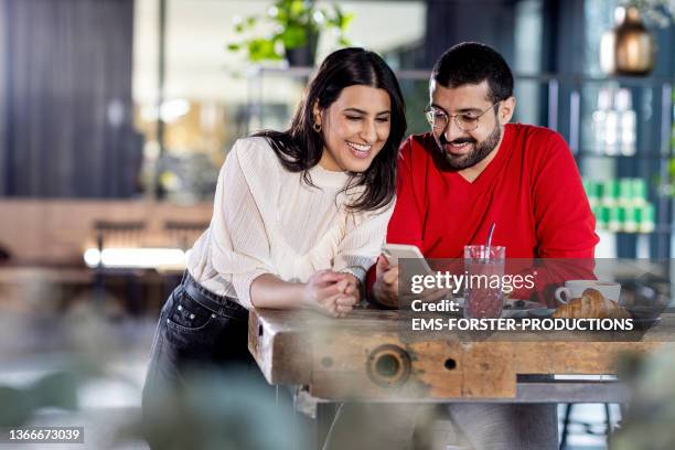 two best friends looking over pictures on smartphone in cafe together - germany best pictures of the day imagens e fotografias de stock