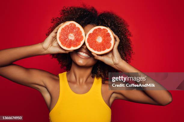 bella donna afro che tiene un pompelmo - pompelmo foto e immagini stock