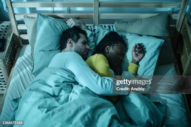 peaceful couple asleep in bed cuddling together - couple sleeping 個照片及圖片檔