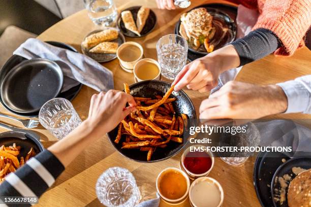 friends eating french fries at restaurant - batata frita - fotografias e filmes do acervo