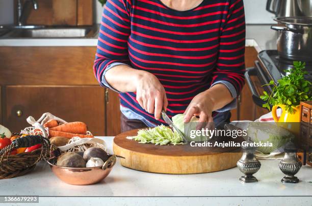 woman cutting a green cabbage. preparing food for cooking soup. - borschtsch stock-fotos und bilder