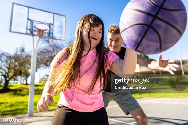 girl with down's syndrome playing basketball with her family - disability stock pictures, royalty-free photos & images