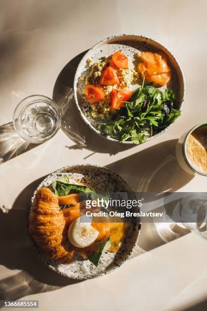 healthy, organic and natural breakfast. croissant, salmon, poached egg, greens, tomato, omelette. glass of water and coffee cup - eierkuchen speise stock-fotos und bilder