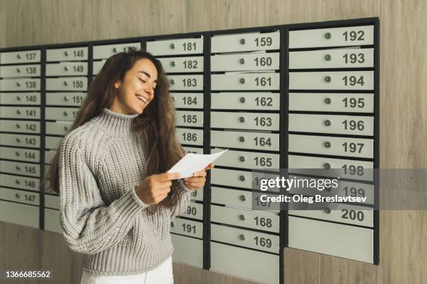 young cheerful woman receiving letter with good news by post. loan is repaid, the debt is paid - letter box stock-fotos und bilder