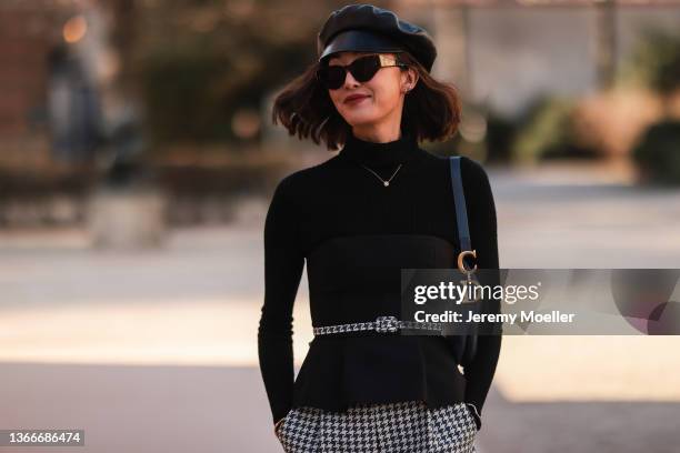 Chriselle Lim is wearing a black blazer and hat and black and white trousers and a black bag, seen outside Dior during Paris Fashion Week Haute...