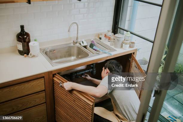 southeast asian repairman working in the kitchen - plug hole stock pictures, royalty-free photos & images