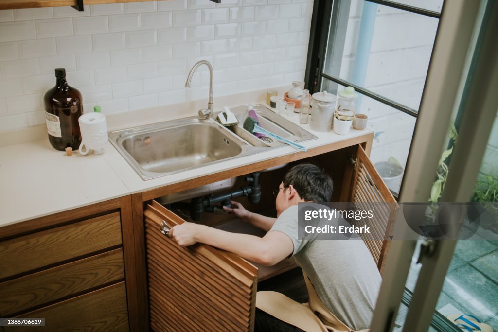 Southeast Asian repairman working in the kitchen